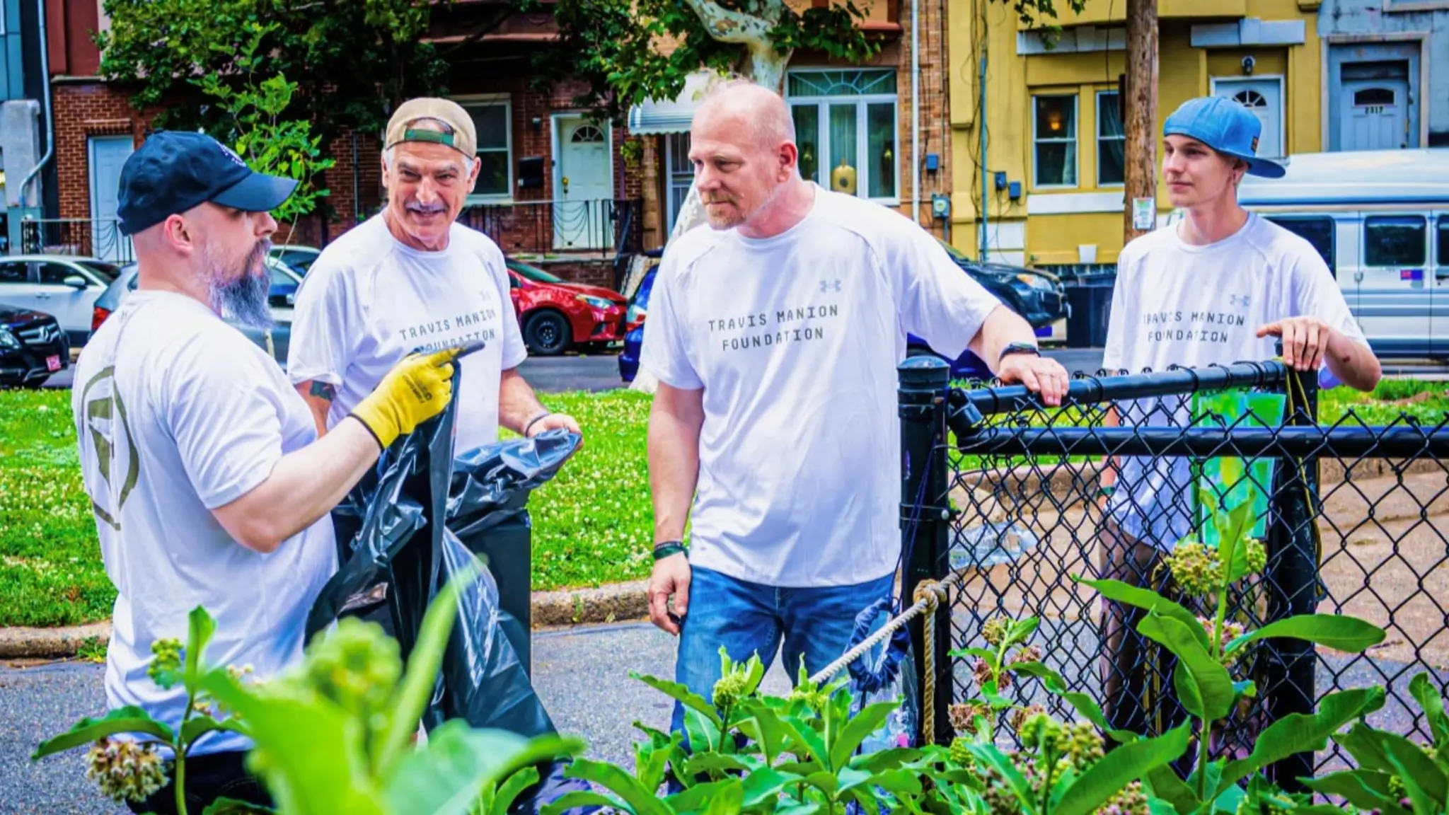 Four Travis Manion Foundation volunteers work together beside a neighborhood garden fence.